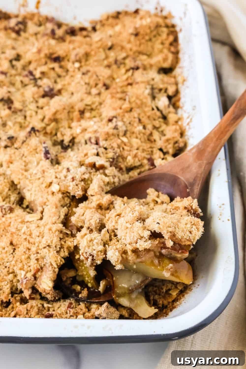 Warm Fresh Pear Crisp Recipe with Cinnamon Oat Topping 4 A wooden spoon scoops out a serving of pear crisp cobbler that's freshly baked in a 9x13
