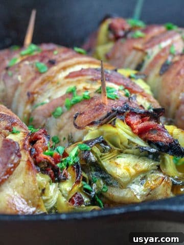 Bacon wrapped stuffed chicken on a skillet.