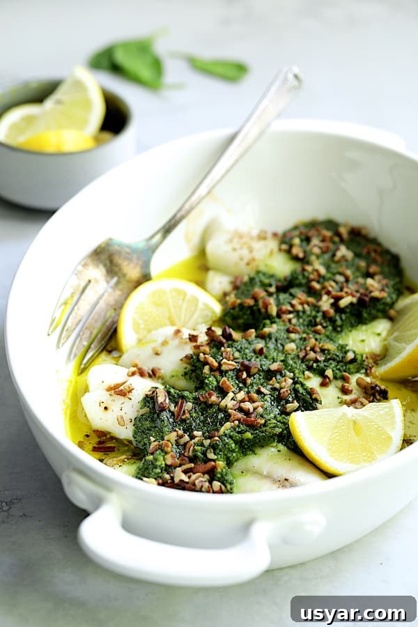 Oven-Baked Tilapia with Spinach Pecan Pesto Recipe 8 Photo of Baked Tilapia with Spinach Pecan Pesto in white baking dish with serving fork.