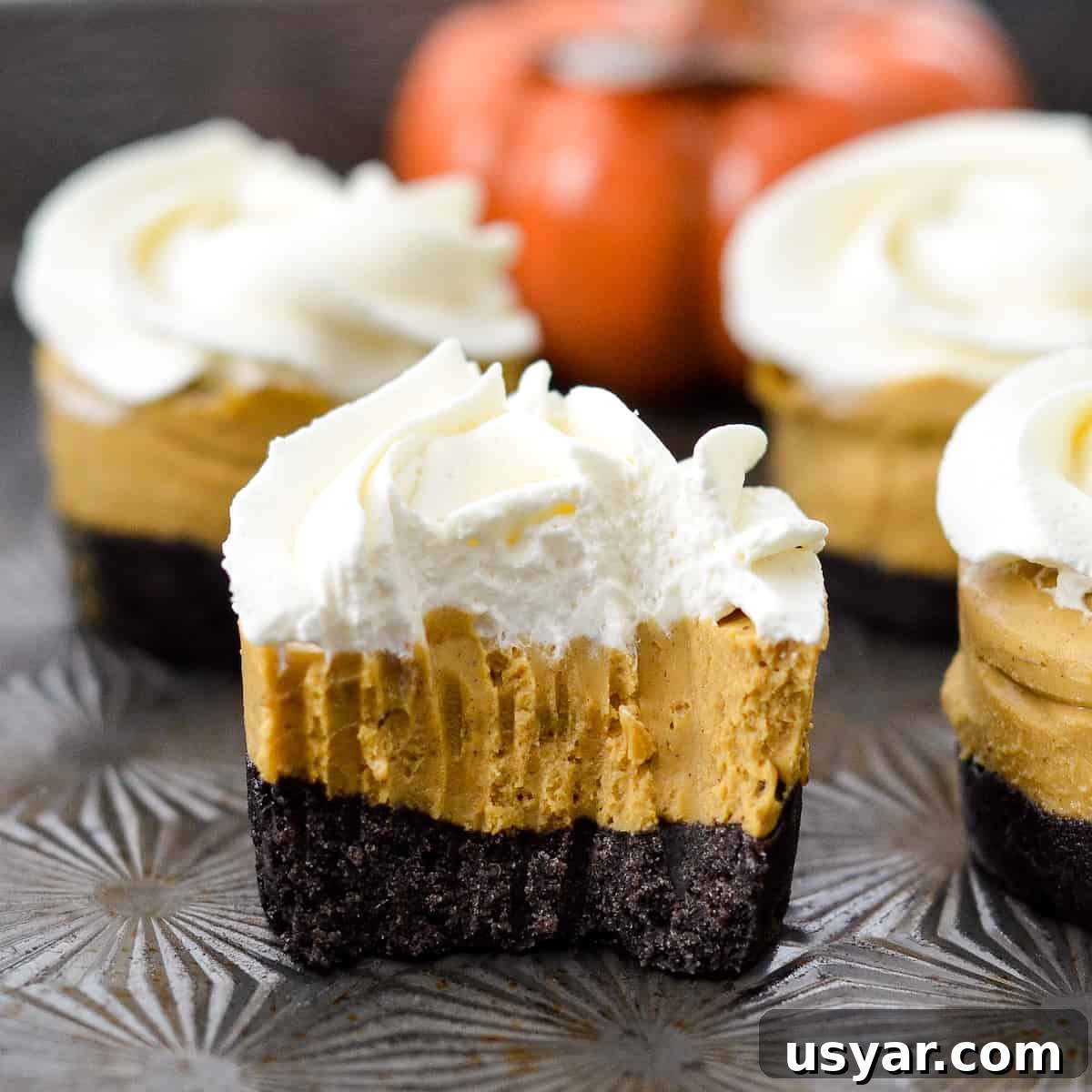 No-Bake Mini Vegan Pumpkin Pies are the perfect elegant fall dessert! They are gluten-free, dairy-free, refined sugar free, paleo, vegan and SUPER easy to make! #vegan #pumpkinpie #nobake #dessert #paleo #glutenfree #dairyfree 4 vegan pumpkin bites with one half eatten.