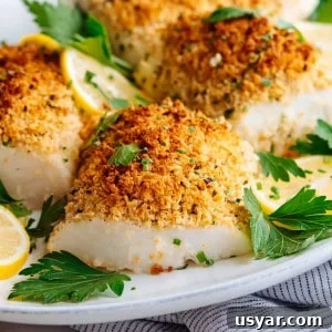 Parmesan Baked Cod with Garlic and Lemon 11 parmesan baked cod served with parsley and lemon slices on a white oval platter.