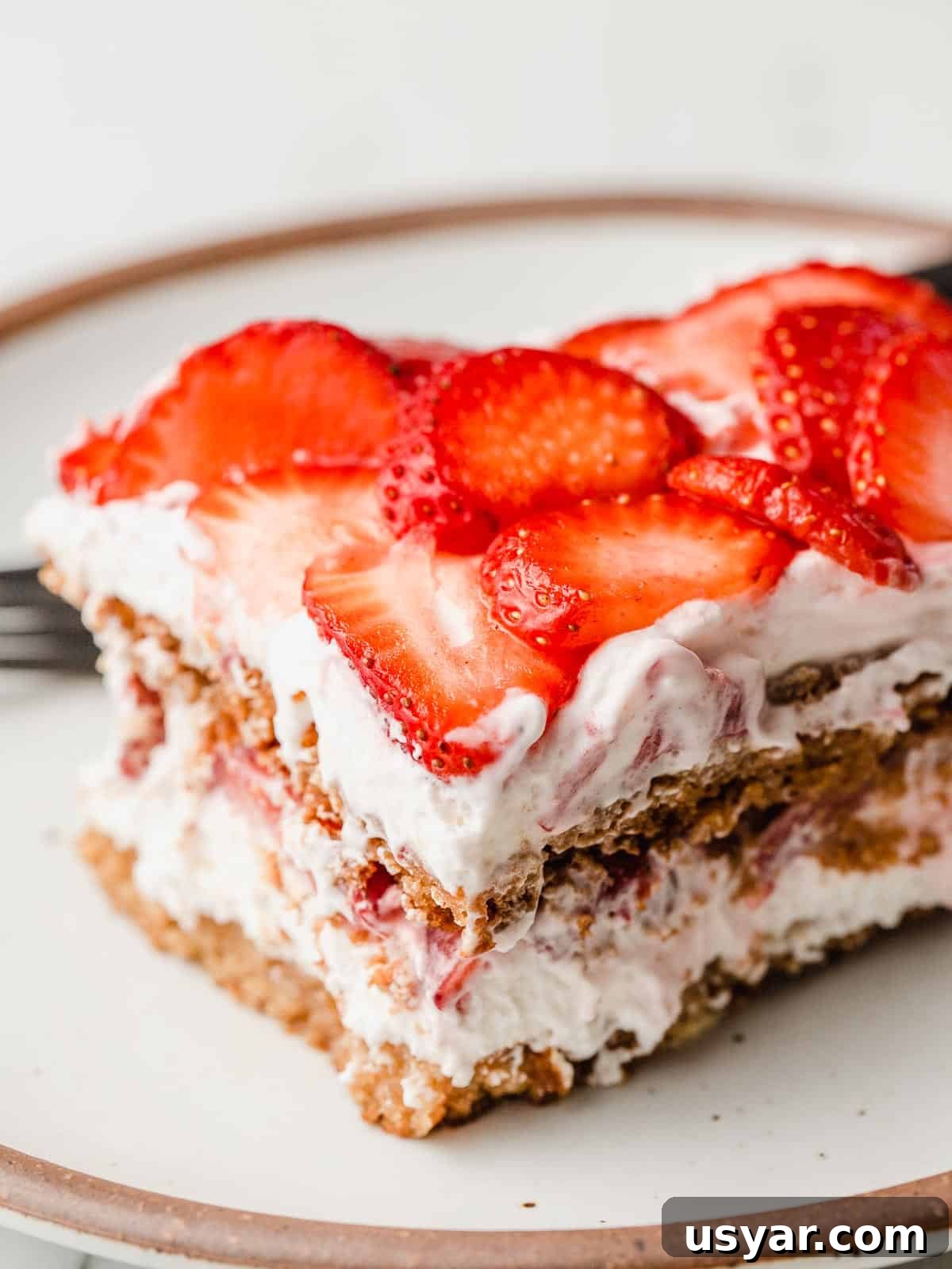No-Bake Gluten-Free Strawberry Icebox Cake Recipe 2 A slice of gluten-free strawberry icebox cake on a plate.