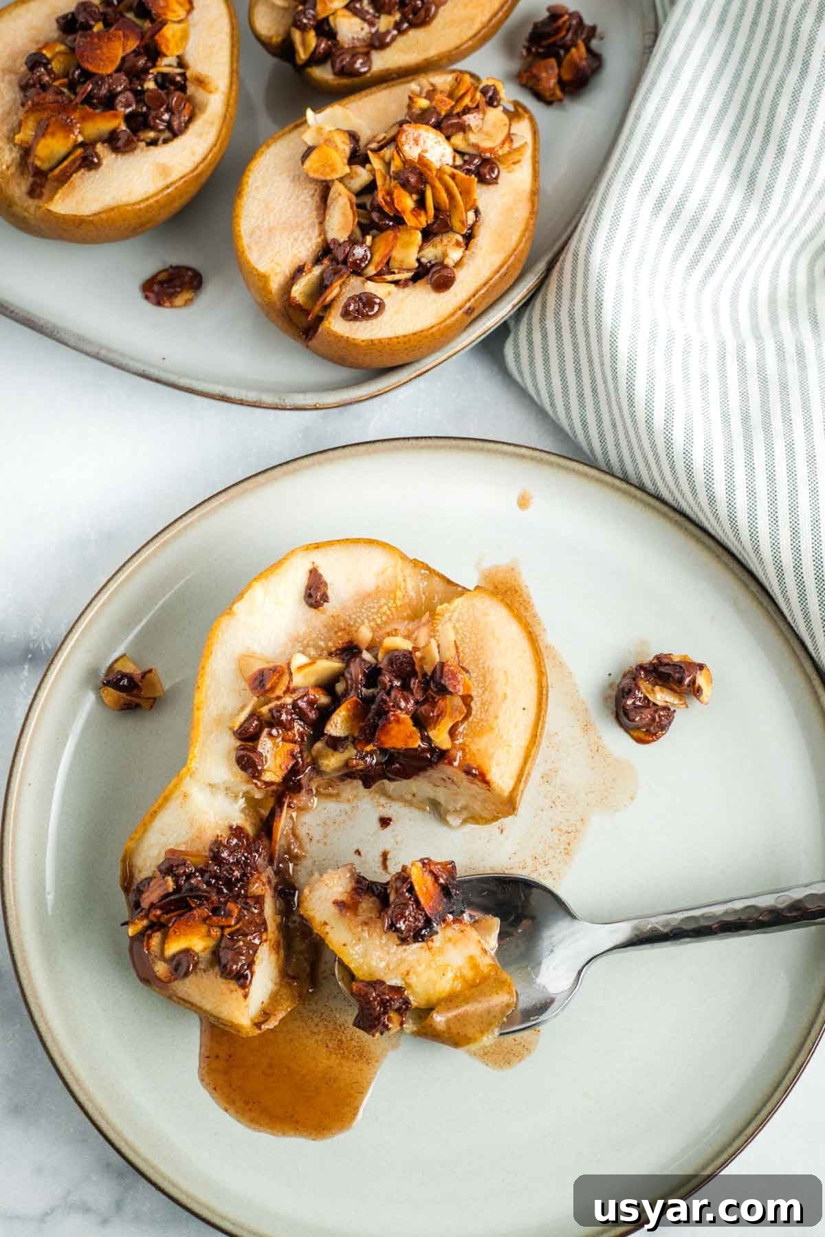 Oven Baked Pears with Almonds and Dark Chocolate 2 Pear half stuffed with almonds, chocolate and honey, oozing out juice when a spoonful is taken.