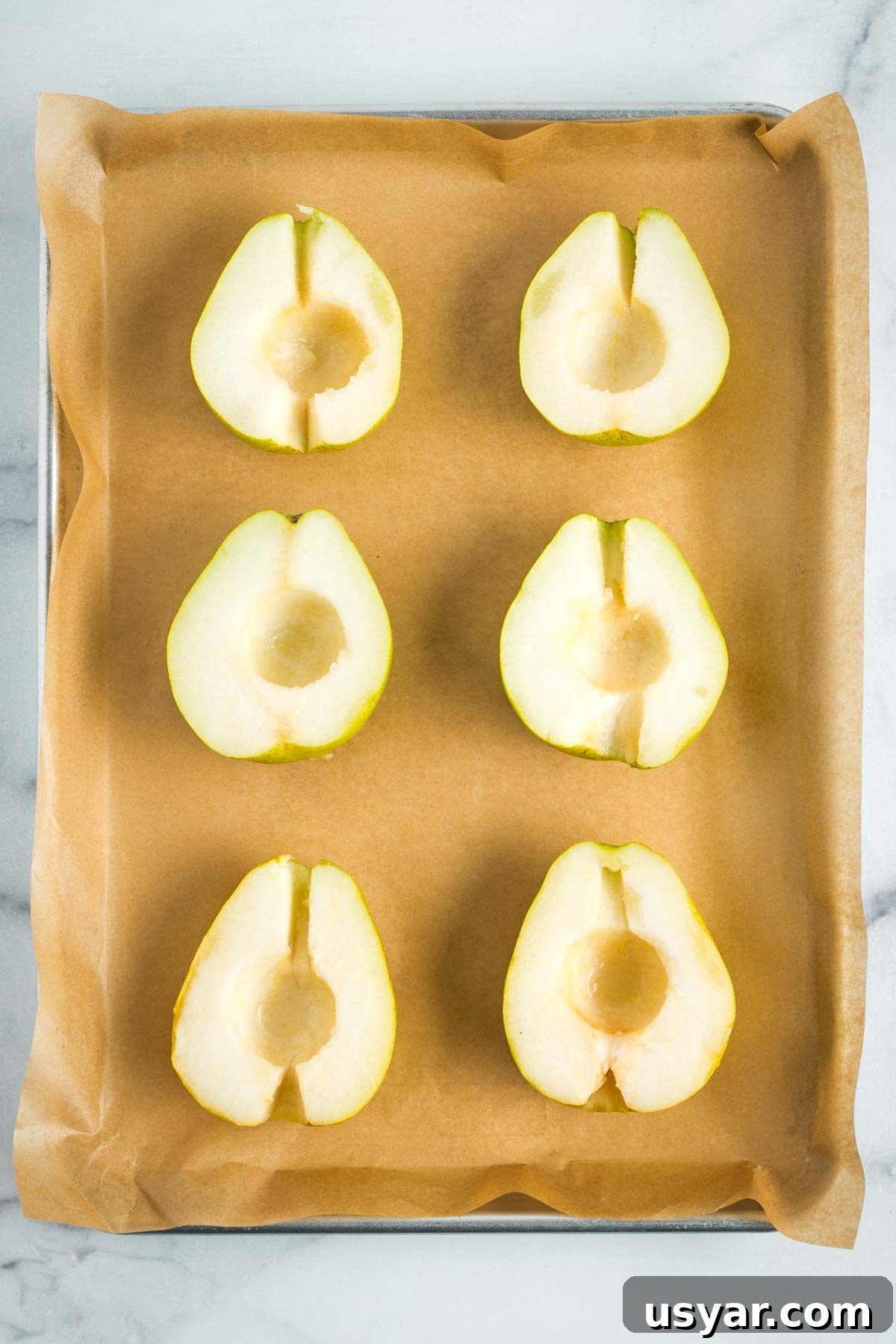 Oven Baked Pears with Almonds and Dark Chocolate 8 3 pears, halved and cored, sitting on a parchment lined baking sheet.