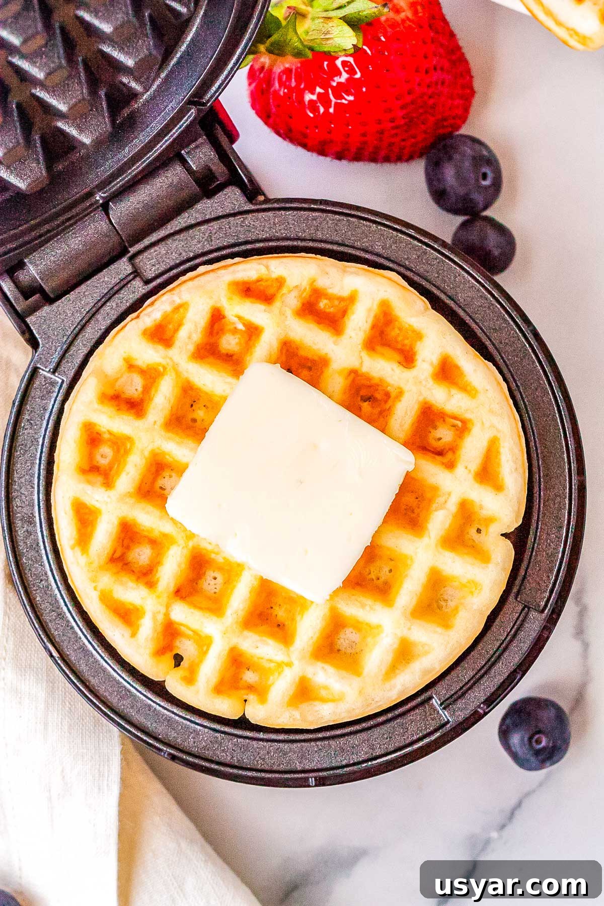 Dash Waffle Maker Recipes for Breakfast, Brunch and Snacks 2 The finished Dash waffle make recipe in the waffle maker with a pad of butter on top of the waffle.