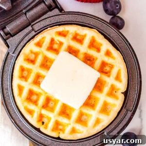The finished Dash waffle make recipe in the waffle maker with a pad of butter on top of the waffle.