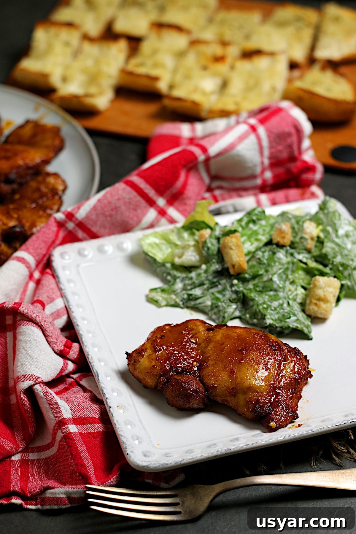 Hot Honey-Glazed Chicken Thighs Recipe 4 A Hot Honey Glazed Chicken Thigh on a white plate.