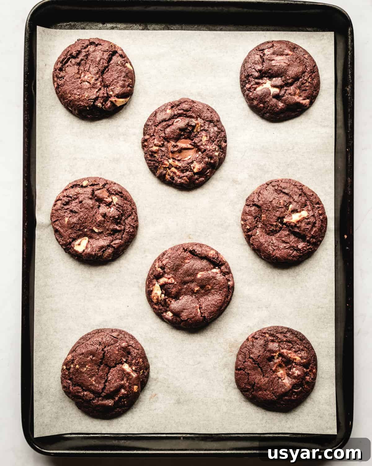 Fudgy White Chocolate Chip Cookie Recipe 4 white chocolate chip chocolate cookies on a baking sheet
