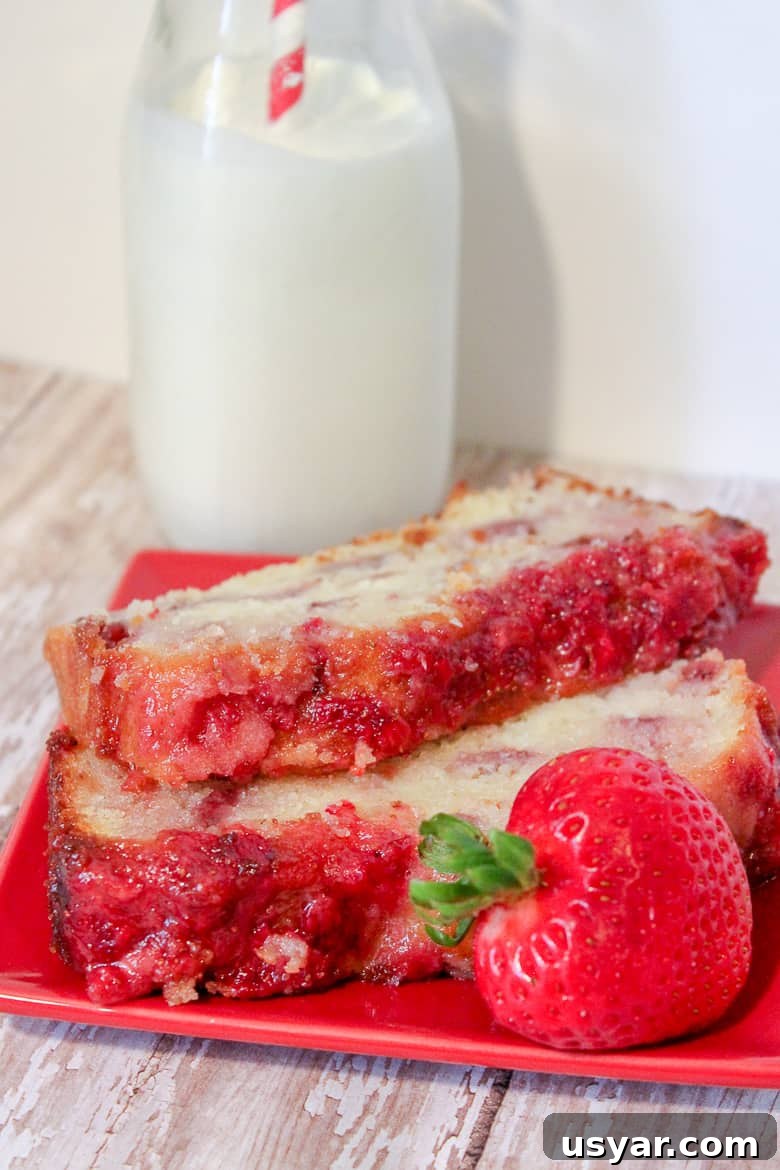 Strawberry Yogurt Pound Cake Recipe 4 2 slices of strawberry pound cake on a red plate with a strawberry on the side. A glass of milk with a red and white straw is in background.