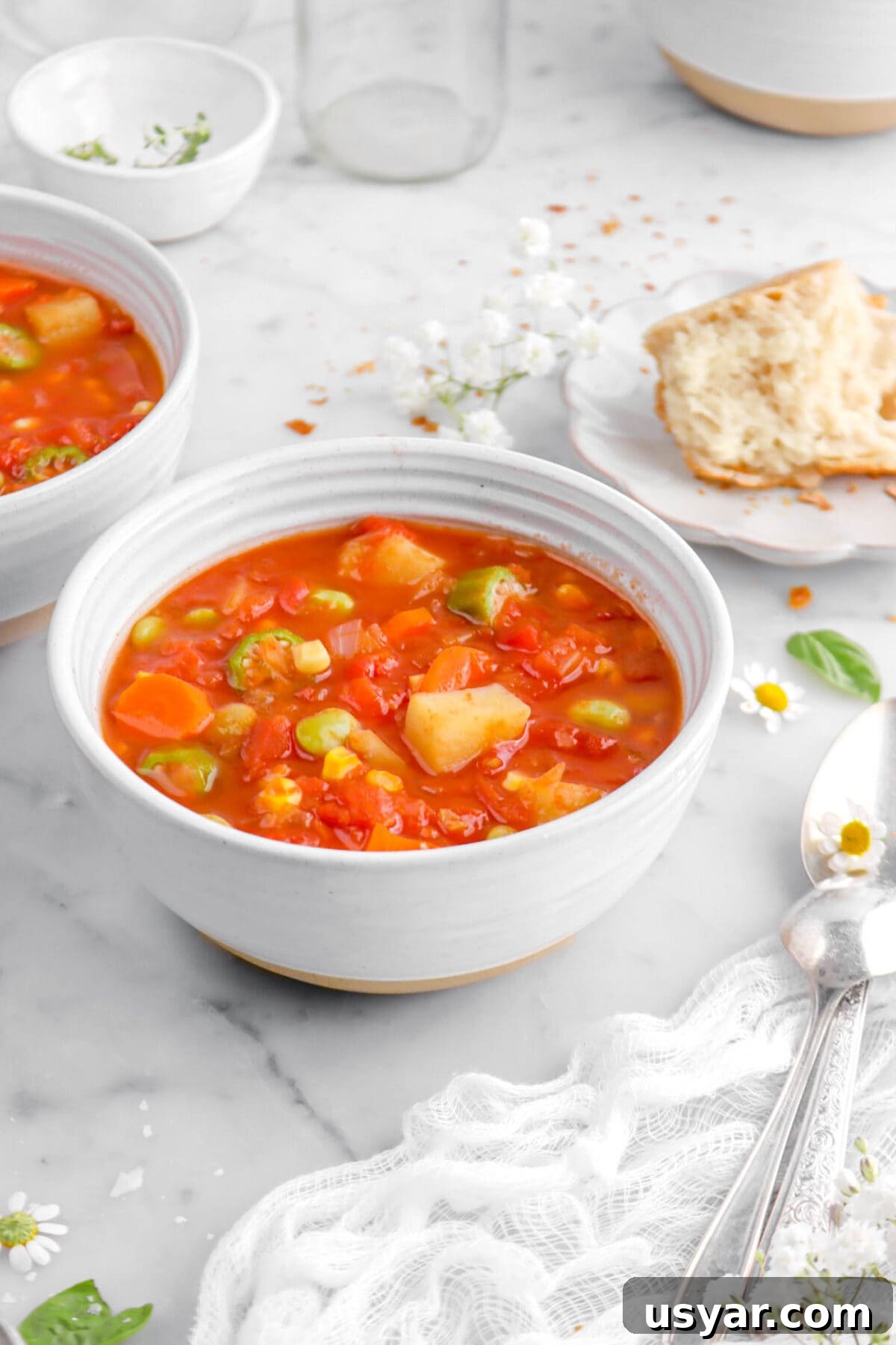 One-Pot Gluten-Free Vegan Vegetable Soup Recipe 3 cropped close up of bowl of vegetable soup with white cheesecloth and two spoons beside.