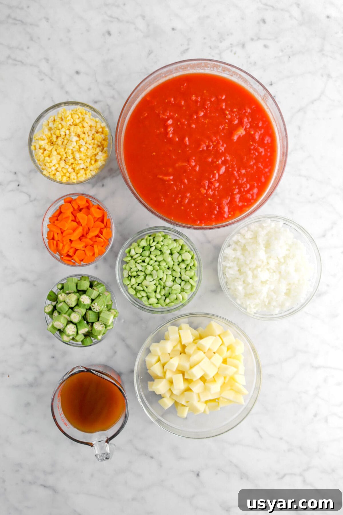 One-Pot Gluten-Free Vegan Vegetable Soup Recipe 4 corn, chopped tomatoes, carrots, lima beans, okra, chopped onion, chopped potatoes, and vegetable broth on marble surface.
