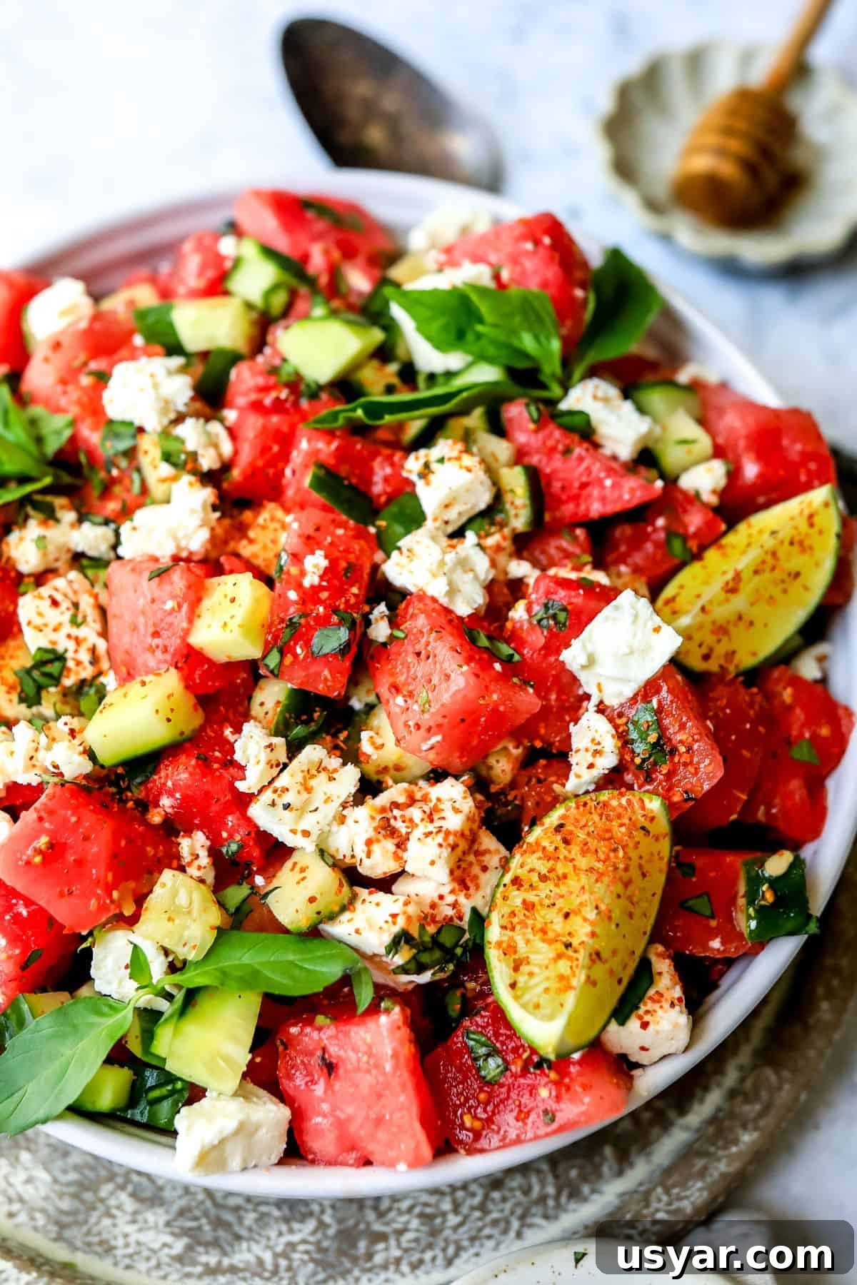 Refreshing Watermelon Basil Salad Recipe 5 Up close up photo of watermelon salad with feta and limes and basil in a white ceramic bow.