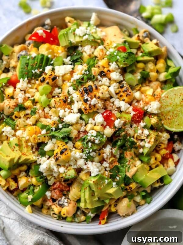 Mexican Street Corn Pasta Salad in a white ceramic bowl with a spicy lime on top.
