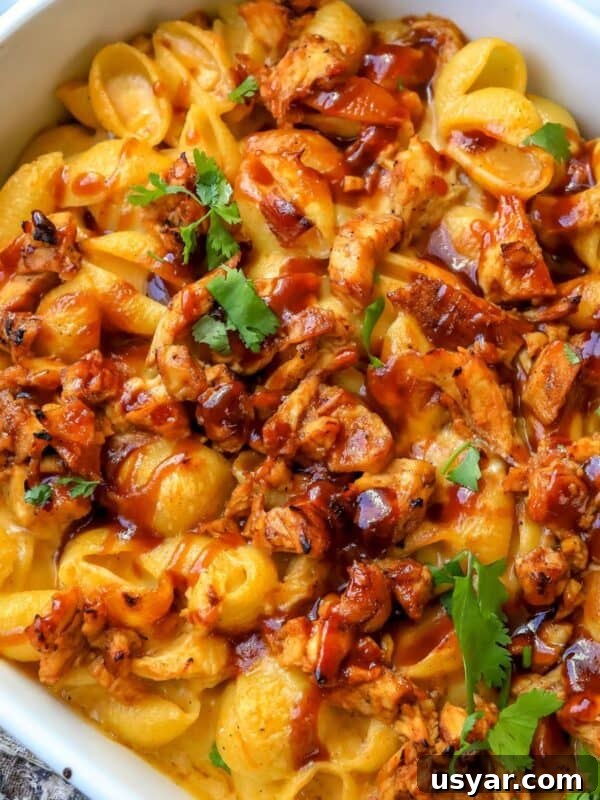 Close up of mac and cheese with bbq chicken mixed in in a white baking dish.