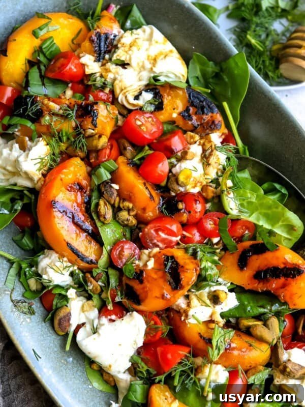 Grilled peach burrata salad on greens in a serving platter.