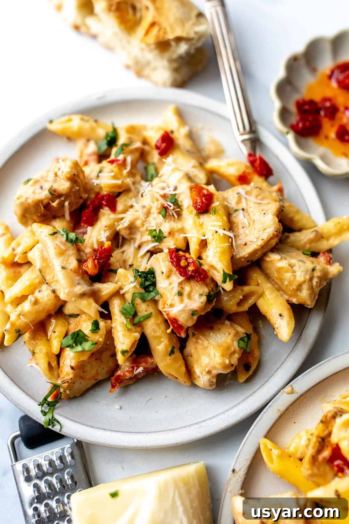 White ceramic plate with marry me chicken pasta on it and silver fork to the side.