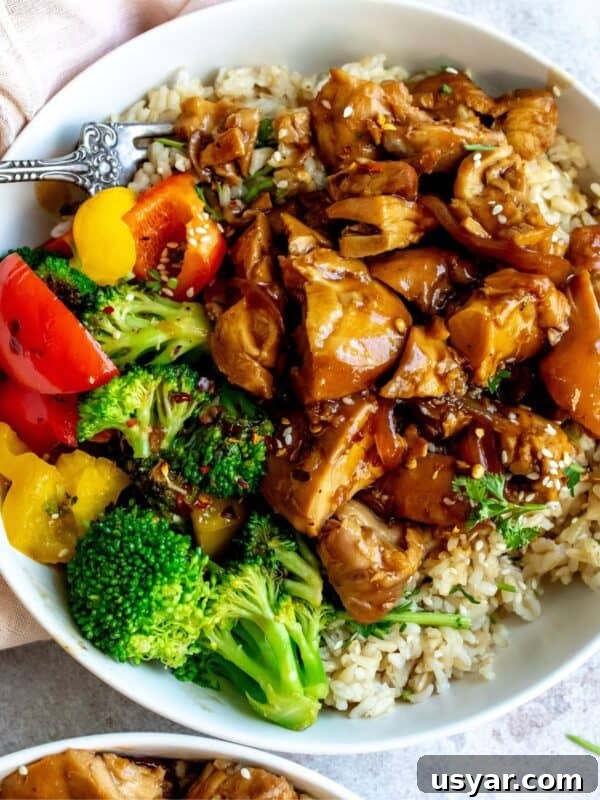 Teriyaki chicken thighs in a white bowl with a fork.