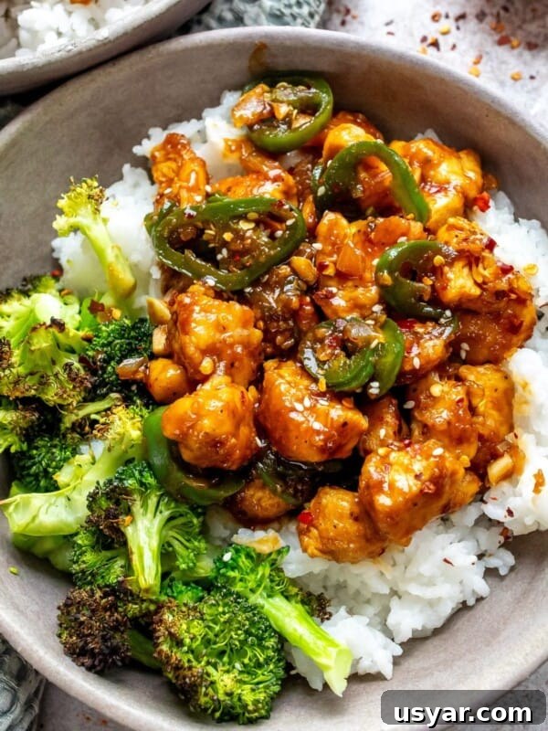 Grey bowl with jalapeño chicken and sauce in it served over rice with a fork.