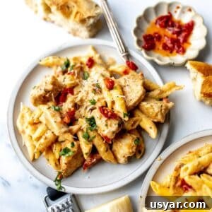 White ceramic plate with marry me chicken pasta on it and silver fork to the side.