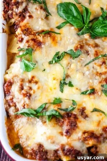 A casserole dish of Rigatoni al Forno garnished with fresh basil leaves.
