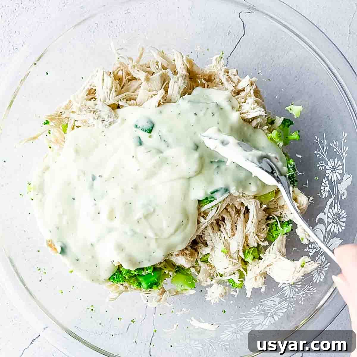 Creamy Chicken Alfredo Stuffed Shells with Spinach 7 Alfredo sauce added to a bowl with shredded chicken and broccoli.