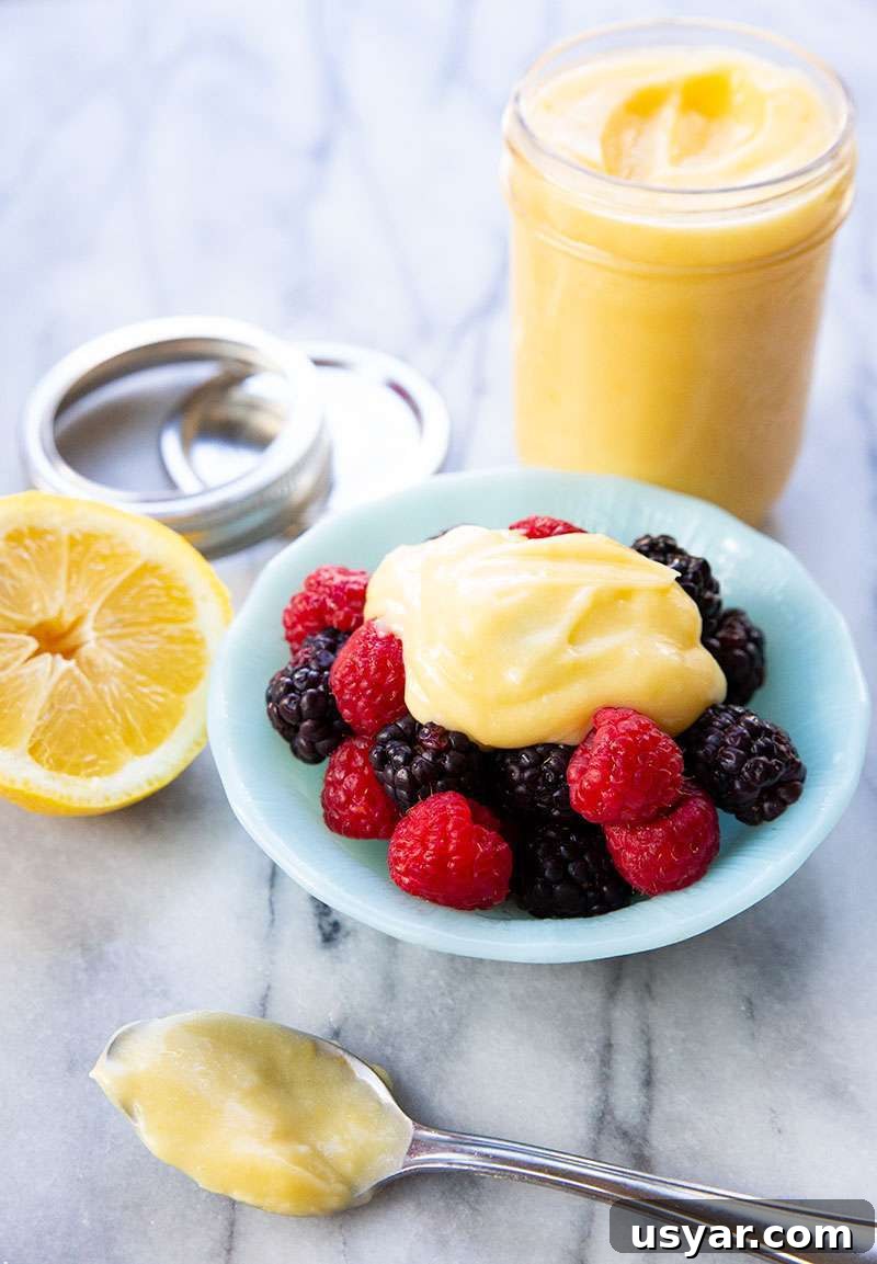 Close up shot of the sugar free lemon curd in a bowl and a jarred batch in the background.