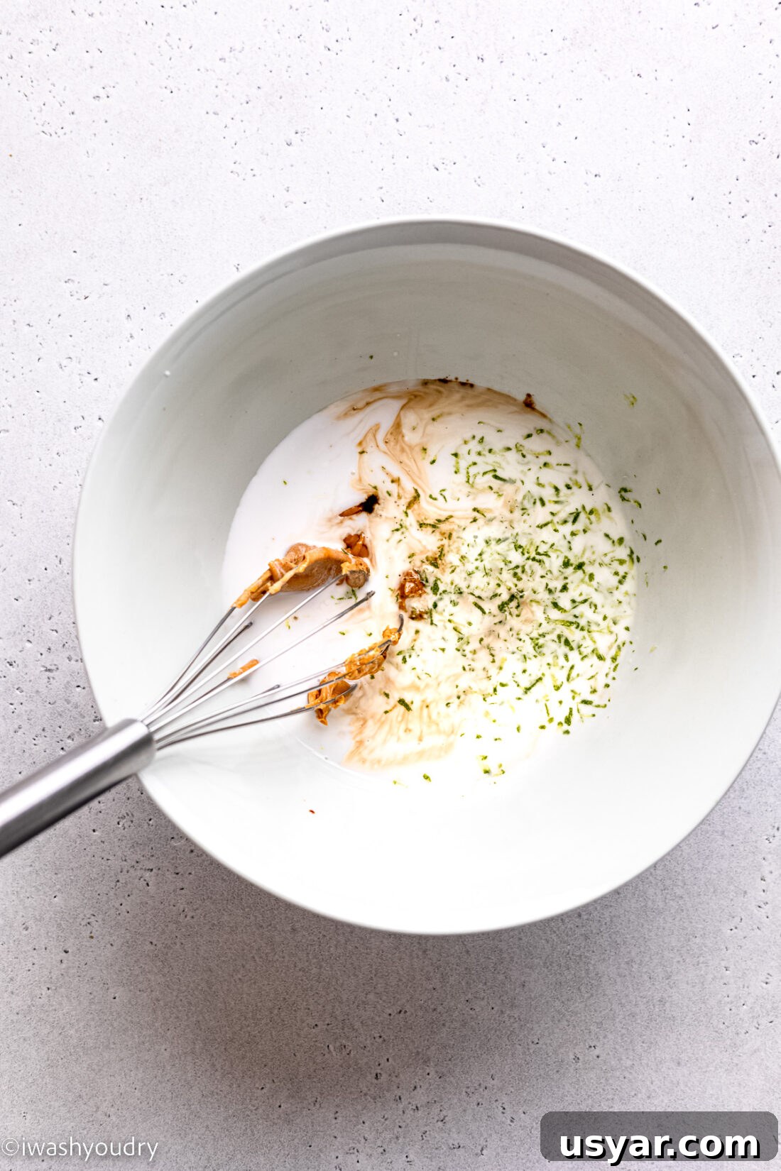 Thai Chicken Satay Recipe with Peanut Dipping Sauce 5 Thai chicken satay marinade in a white bowl with whisk.
