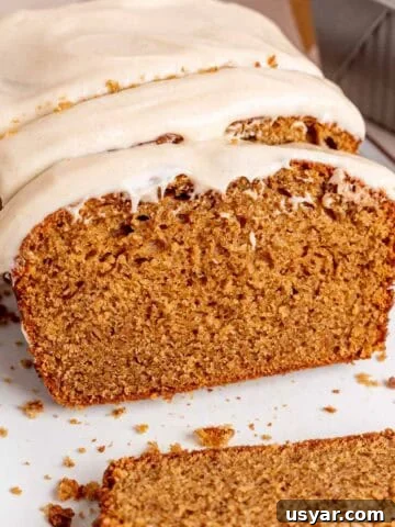 A loaf of spice cake with brown butter cream cheese frosting cut into slices.