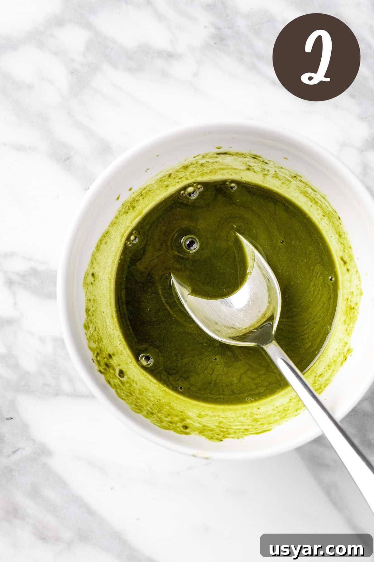 Oat Milk Matcha Latte Recipe 5 A process photo illustrating step 2: mixing the maple syrup and honey into the matcha.