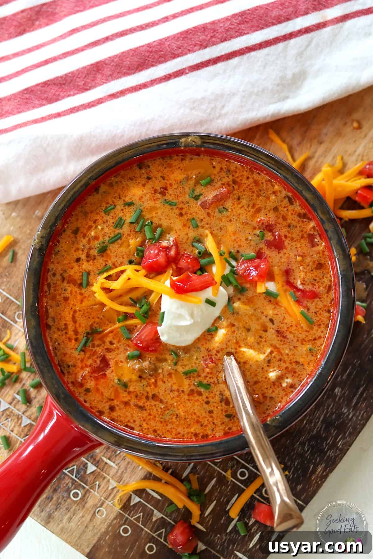 Beef Taco Soup with Ground Beef and Beans 2 A red bowl of creamy taco soup garnished with sour cream, cheese, and green onion.