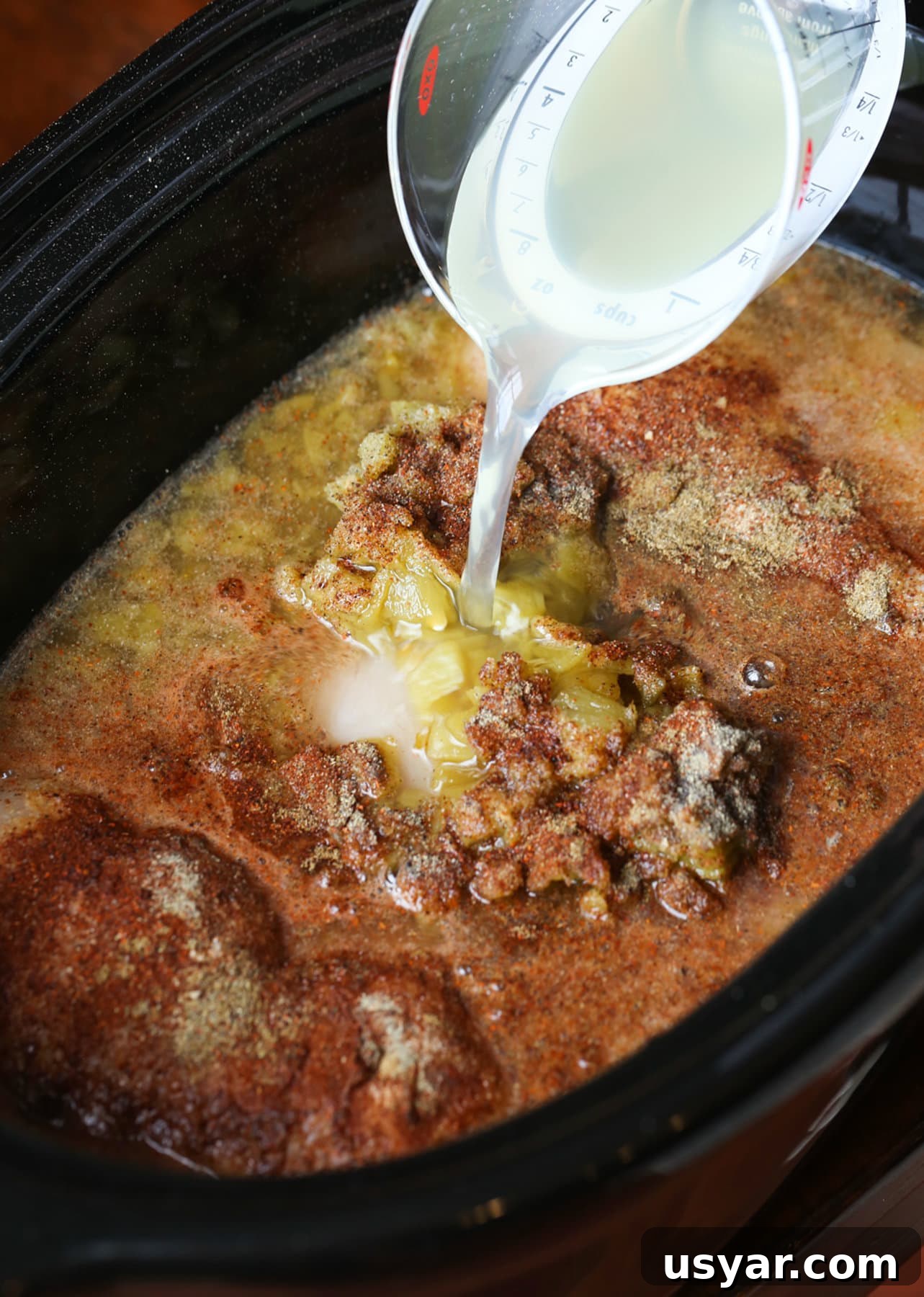 This Beergarita pulled chicken is a citrus, Tex-Mex, flavor-packed pulled chicken recipe! Sweet and smoky, this easy Crock Pot chicken recipe is great on tacos, over rice, in quesadillas and beyond! Pouring margarita mix into a slow cooker