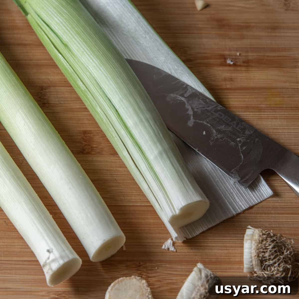 Creamy Vegan Leek and Potato Soup Vichyssoise 5 Photo of the peeling off the outer skin of the leeks on a chopping board.
