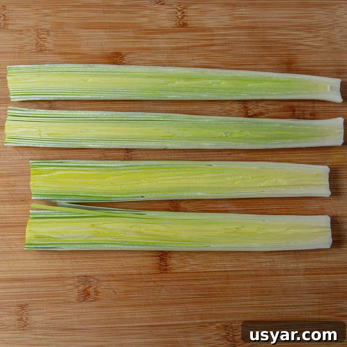 Creamy Vegan Leek and Potato Soup Vichyssoise 6 Photo of two leeks on a chopping board, sliced in half vertically and lying in a row on the board.