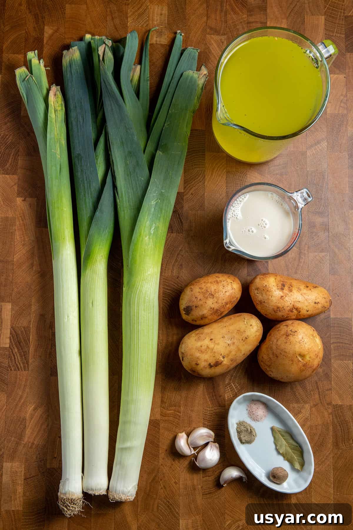 Creamy Vegan Leek and Potato Soup Vichyssoise 8 Photo of the ingredients for this vegan leek and potato soup laid out on a wooden surface.