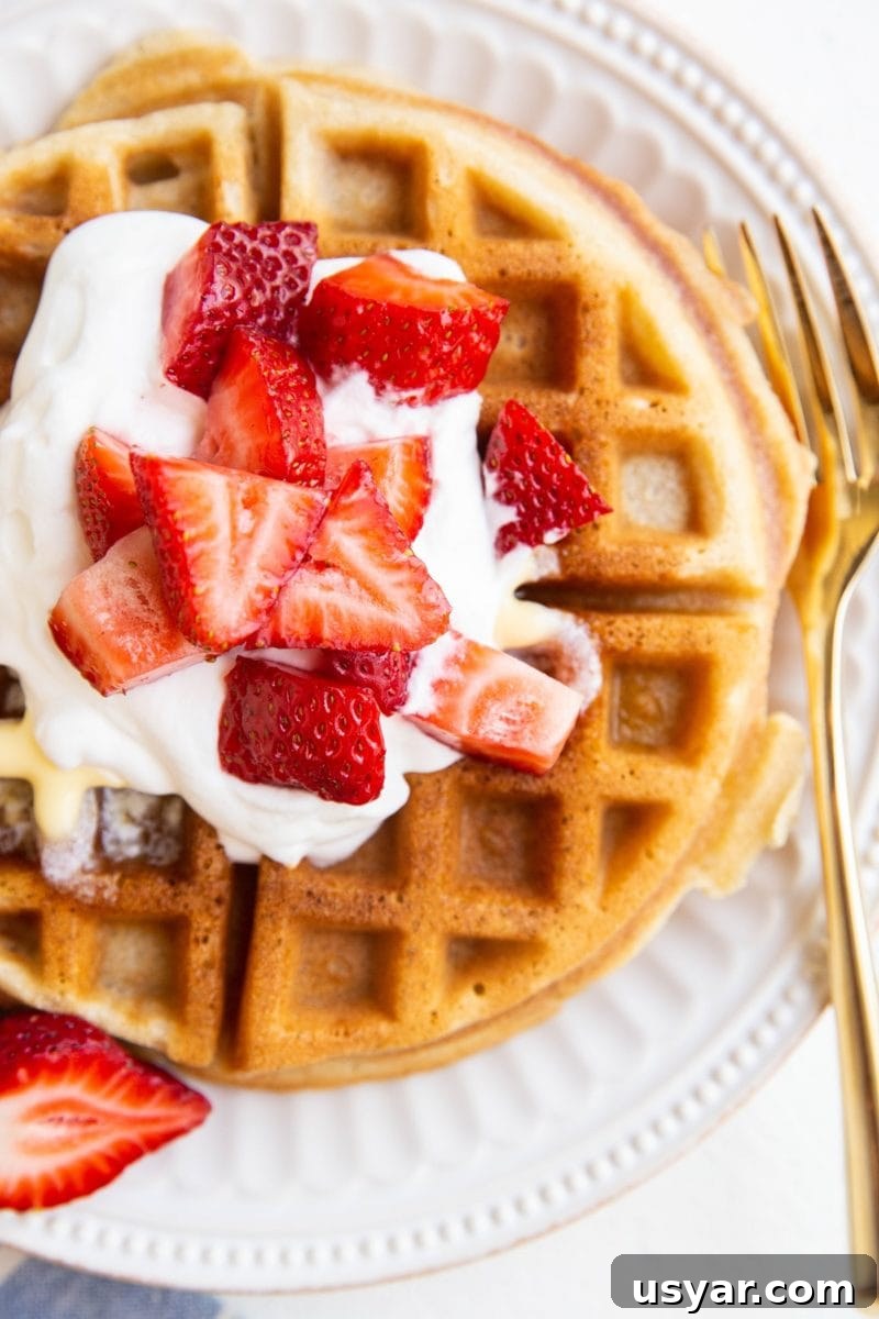 Close up top down photo of waffles with strawberries and whipped cream