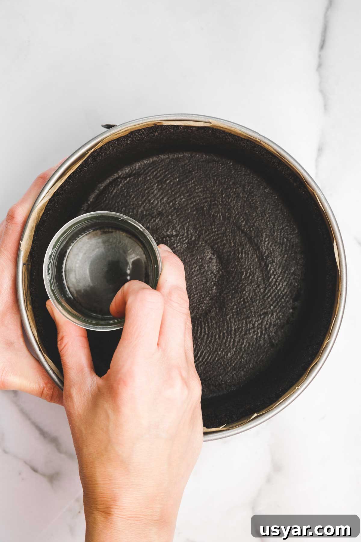 springform pan with pressed oreo crust before baking