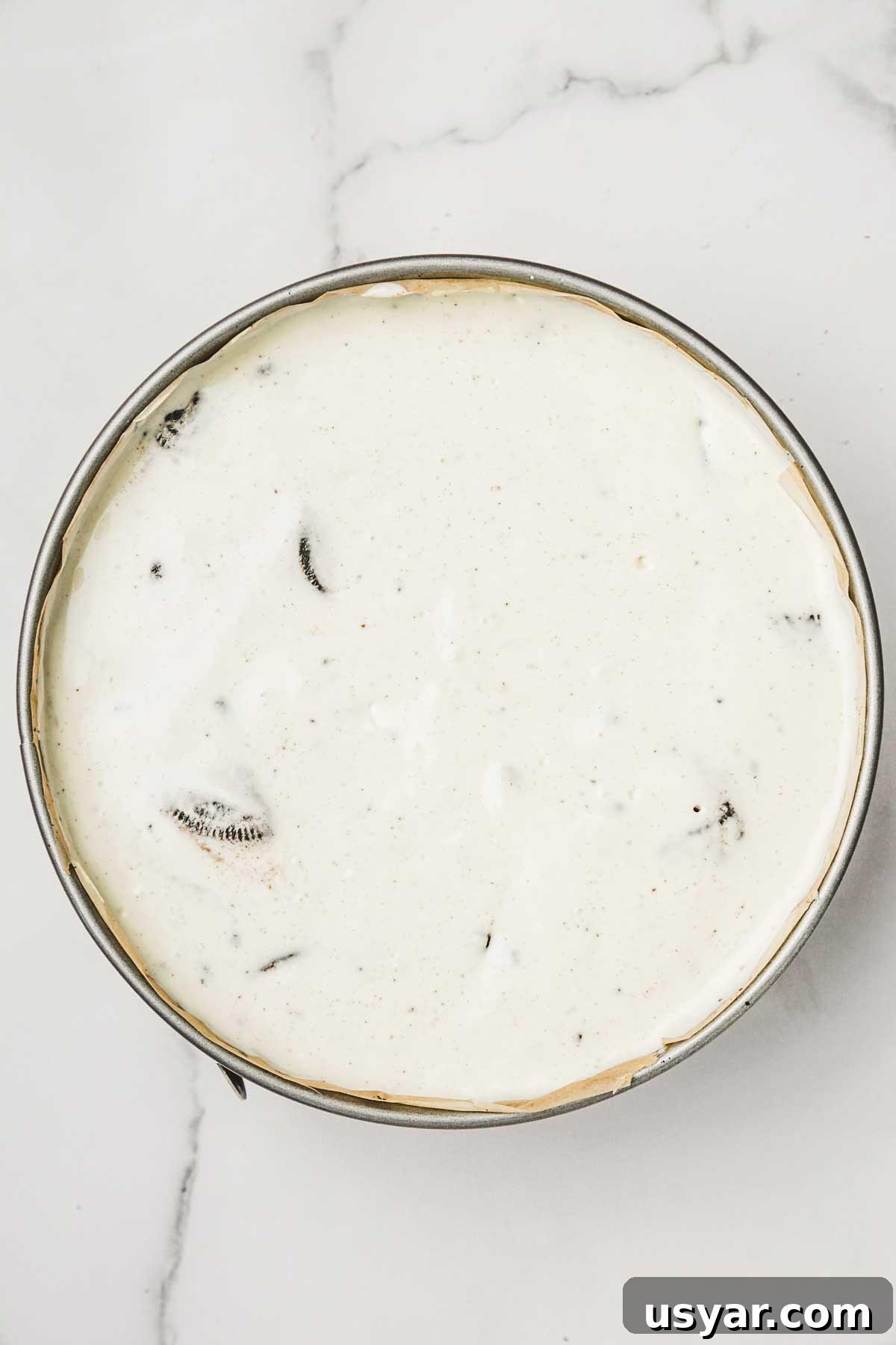 cheesecake batter poured into pan over oreo crust