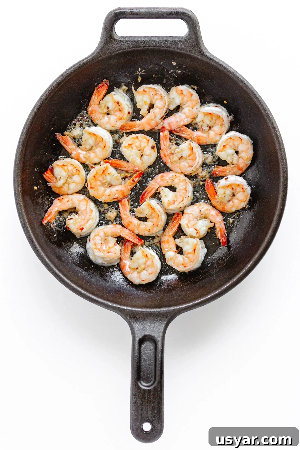 Shrimp being sauteed in a cast iron skillet.