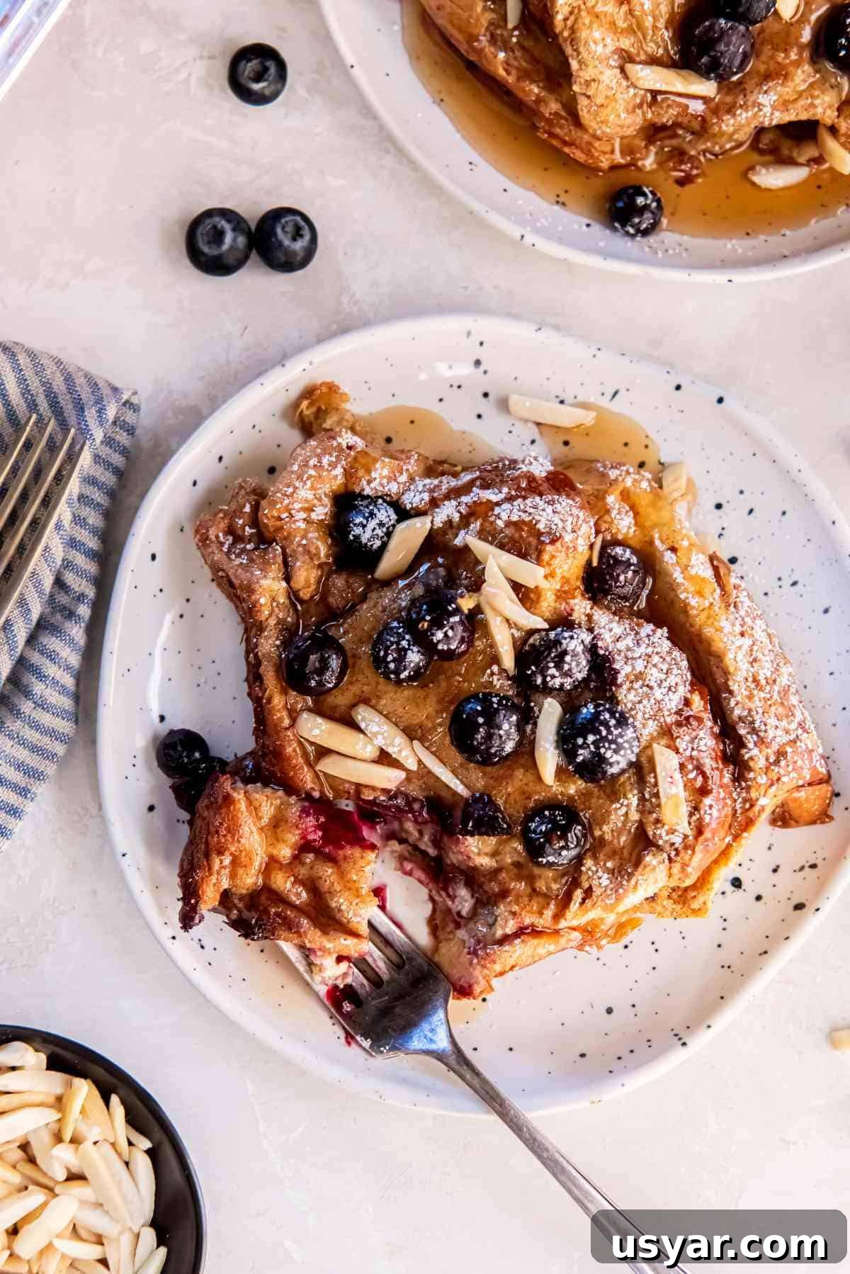 Overhead view of blueberry brioche French toast bake topped with blueberries and sliced almonds