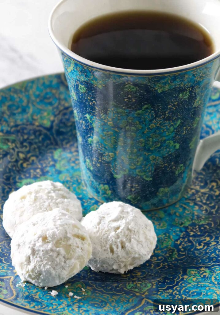 Mexican Snowball Cookies Recipe (Polvorones) 8 Three snowball cookies on a plate with a cup of coffee.