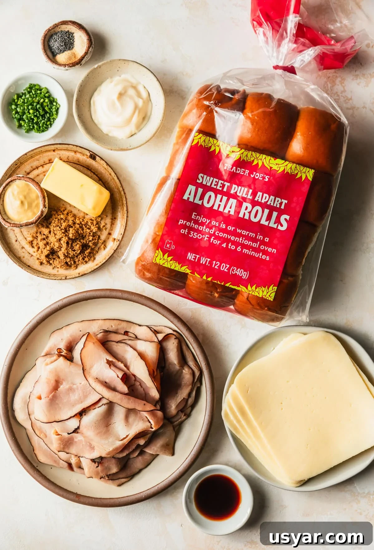 Oven Baked Brown Sugar Ham and Cheese Sliders 3 Brown and white bowls of ham, cheese, Worcestershire, brown sugar, butter, mustard, mayo, chives, and spices next to Hawaiian rolls on a tan counter.