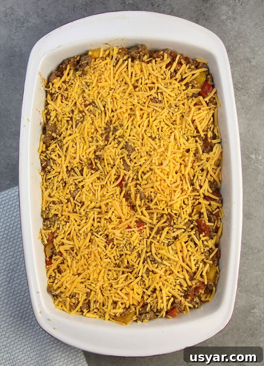 The mixture of meat, farro, and peppers topped with cheese in a baking dish for unstuffed pepper casserole.