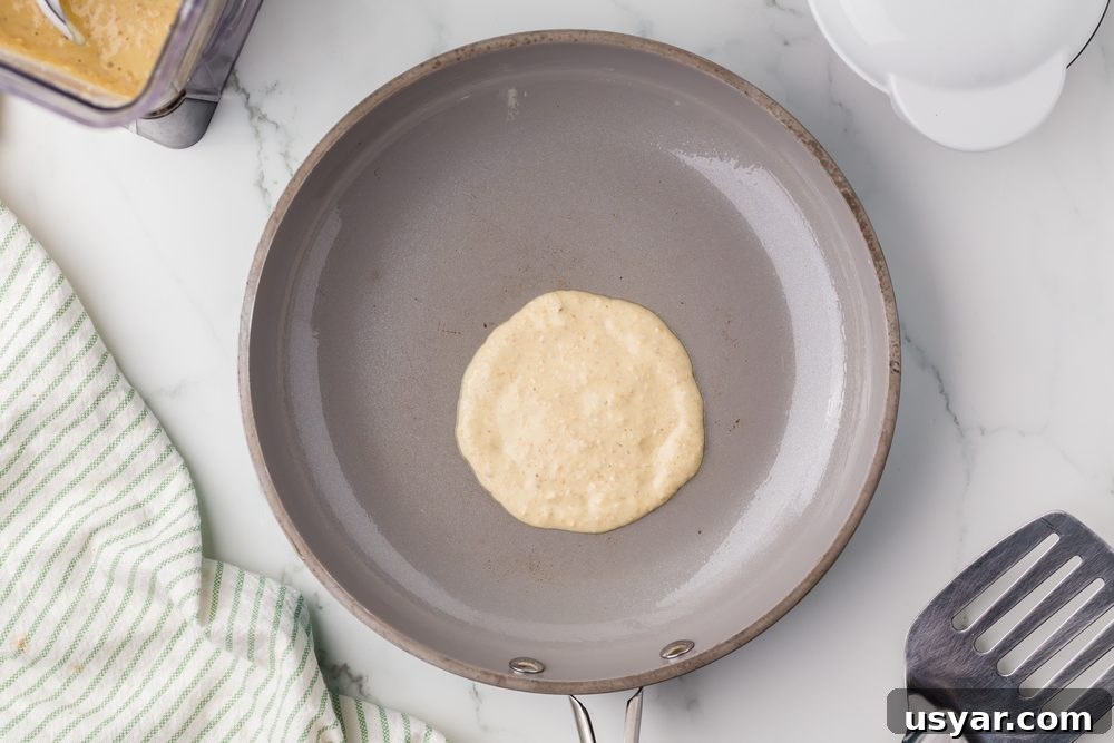 High Protein Cottage Cheese Blender Pancakes 8 One raw pancake in a skillet cooking for blender pancakes recipe post