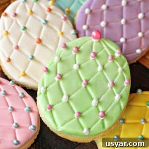 Decorated Fondant Easter Egg Cookies 4 A pile of Fondant-Covered Easter Egg Cookies on a wooden surface.