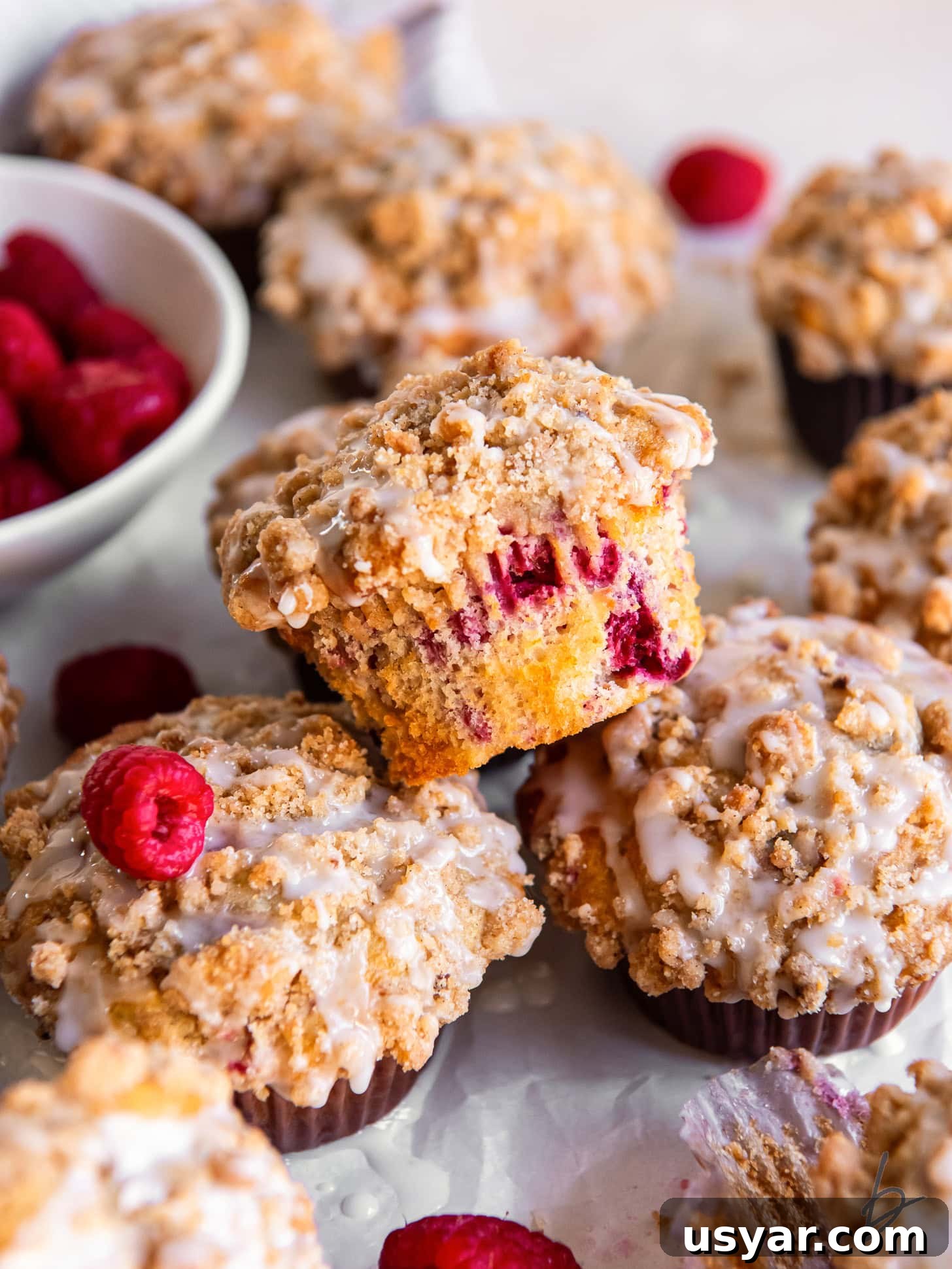 Zesty Lemon Raspberry Streusel Muffins 2 raspberry muffin with streusel on top of two more muffins.