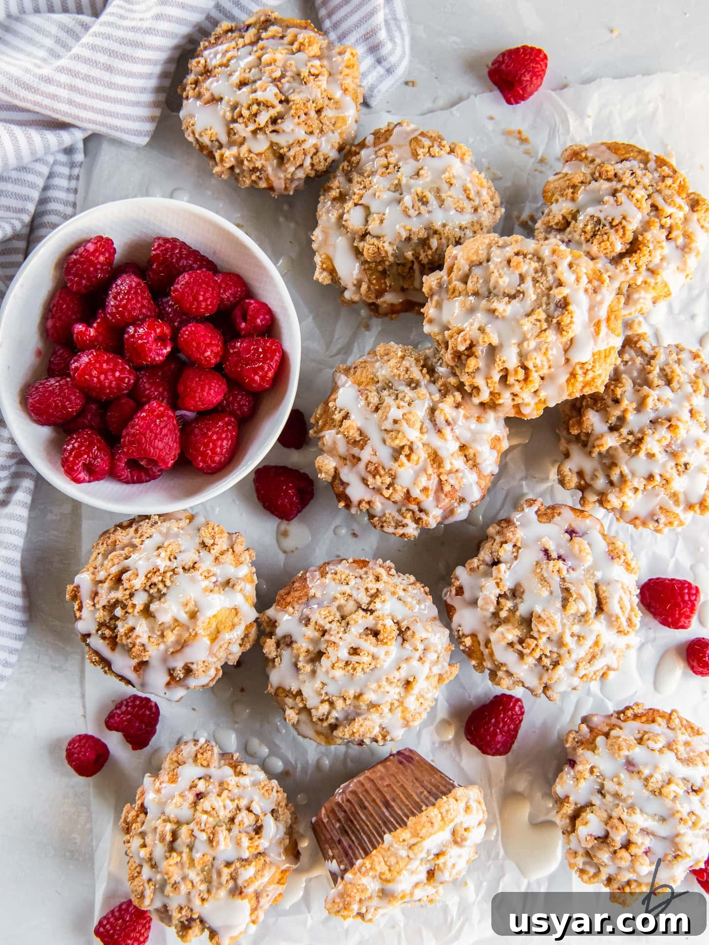 Zesty Lemon Raspberry Streusel Muffins 7 tabletop with raspberry muffins with streusel topping and lemon glaze.