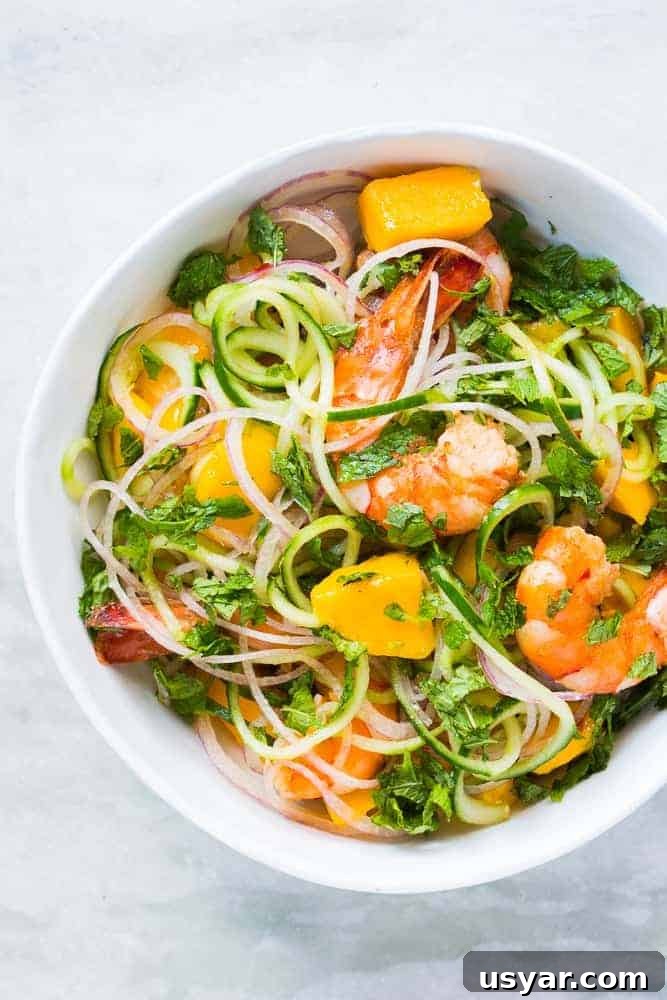 Gluten-Free Shrimp, Cucumber Noodle and Mango Salad 2 cucumber noodle prawn and mango salad served in a bowl