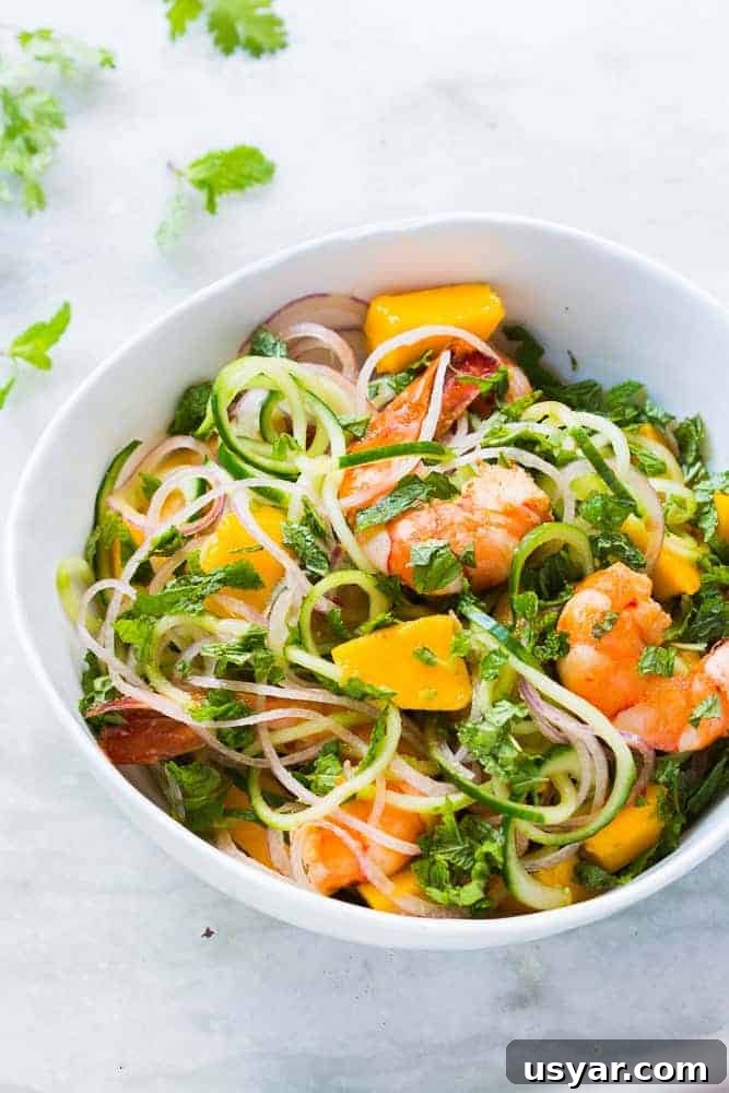 Gluten-Free Shrimp, Cucumber Noodle and Mango Salad 4 cucumber noodle prawn and mango salad served in a bowl
