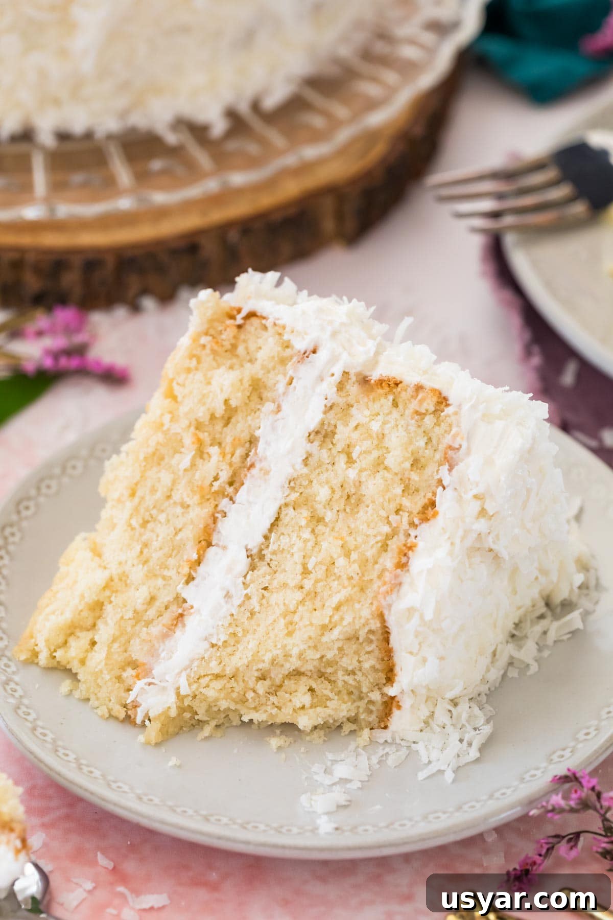 Classic Coconut Cake Recipe with Coconut Cream Frosting 2 Slice of coconut cake on a white plate