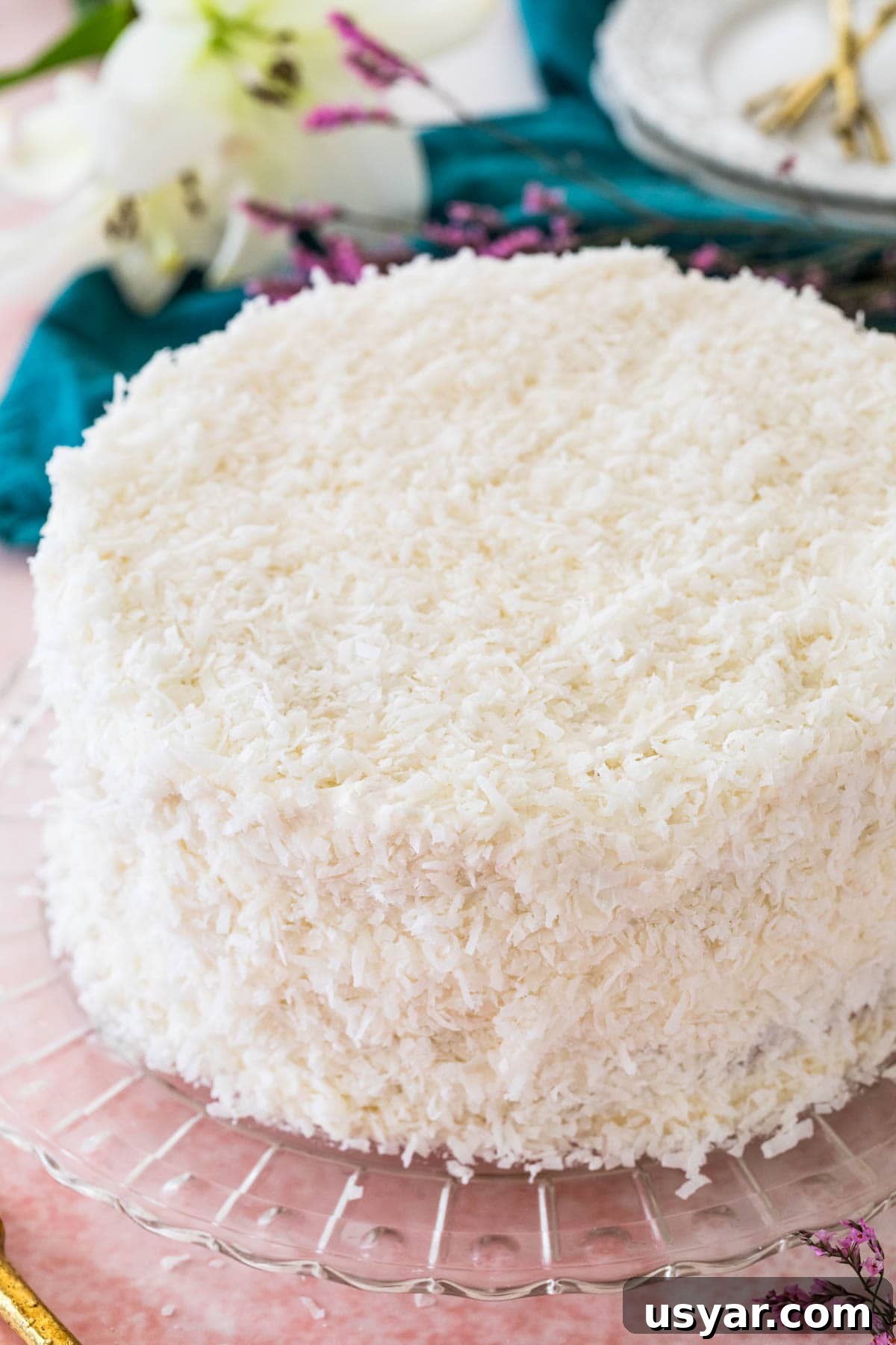 Classic Coconut Cake Recipe with Coconut Cream Frosting 3 Coconut cake on glass platter, covered with shredded coconut